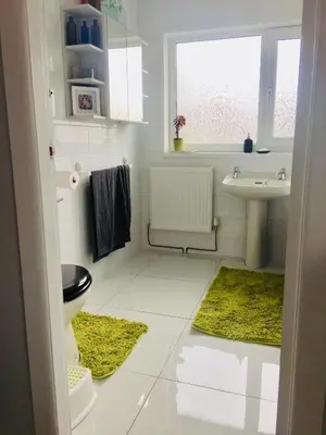 a bathroom with a sink and a toilet and green rugs at Dalmore - Quiet residence with long driveway at M6 Preston in Samlesbury