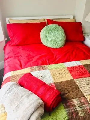 a bed with red pillows and a quilt on it at Dalmore - Quiet residence with long driveway at M6 Preston in Samlesbury