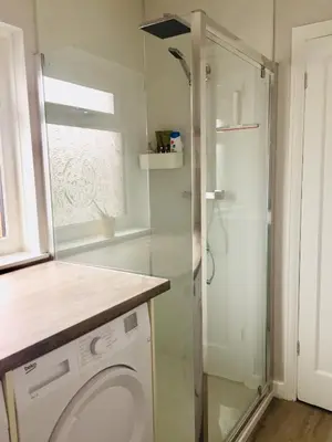 a bathroom with a shower and a washing machine at Dalmore - Quiet residence with long driveway at M6 Preston in Samlesbury