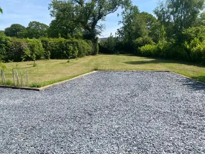a gravel driveway with a grass field and trees at New purpose built holiday lodge in Scorton