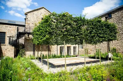 a tree in a garden in front of a brick building at Theodore House in Clitheroe