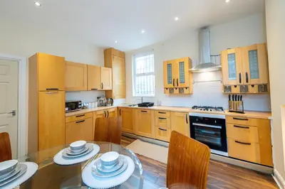 a kitchen with wooden cabinets and a glass table at 10 Guests - Free Parking - City Centre in Liverpool