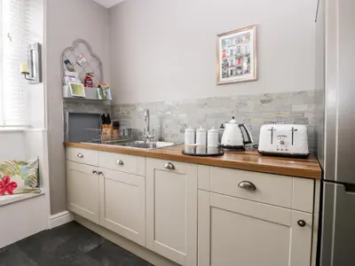 a kitchen with white cabinets and a sink at Cartmel Flat in Grange Over Sands