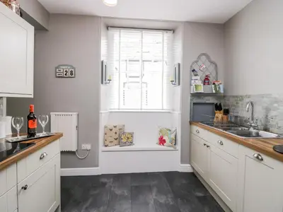 a kitchen with white cabinets and a sink and a window at Cartmel Flat in Grange Over Sands