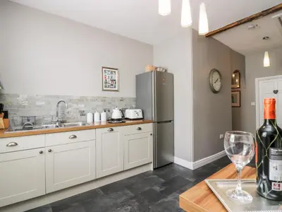 a kitchen with white cabinets and a stainless steel refrigerator at Cartmel Flat in Grange Over Sands