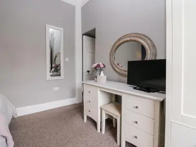 a bedroom with a desk with a tv and a mirror at Cartmel Flat in Grange Over Sands
