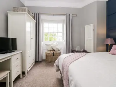a bedroom with a bed and a tv and a window at Cartmel Flat in Grange Over Sands