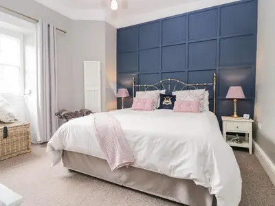 a bedroom with a large bed with a blue headboard at Cartmel Flat in Grange Over Sands