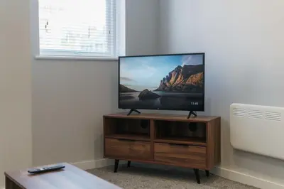 a flat screen tv sitting on a wooden entertainment center at Modern 1 Bedroom Apartment in Liverpool in Liverpool