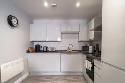 a kitchen with white cabinets and a clock on the wall at Modern 1 Bedroom Apartment in Liverpool in Liverpool