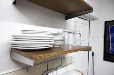 a kitchen with plates and glasses on a shelf at COZY PLACE LIVERPOOL in Liverpool