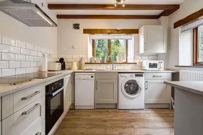 a kitchen with a washer and dryer in it at Manor Farm Barn Cottage in Burton