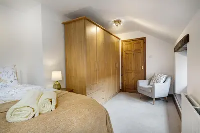 a bedroom with a large bed and a chair at Manor Farm Barn Cottage in Burton