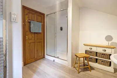 a bathroom with a shower and a wooden door at Manor Farm Barn Cottage in Burton