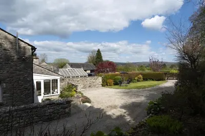 a stone house with a garden and a driveway at Manor Farm Barn Cottage in Burton
