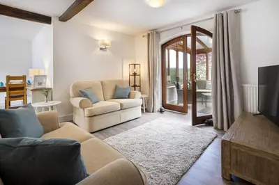 a living room with a couch and a tv at Manor Farm Barn Cottage in Burton