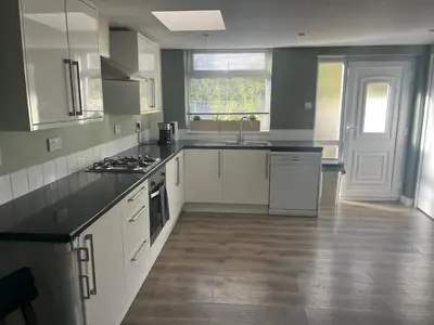 a kitchen with white cabinets and black counter tops at Spacious 2 Bed Ribble Valley Apartments in Blackburn