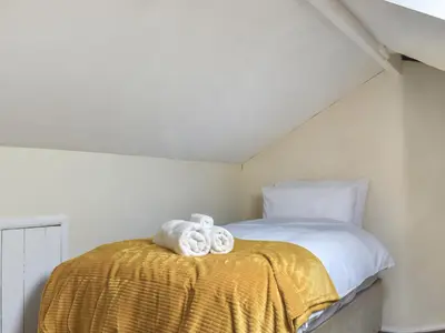 a bedroom with a bed with towels on a yellow blanket at Melrose in Clitheroe