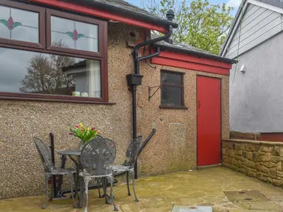 a patio with a table and chairs and a red door at Melrose in Clitheroe