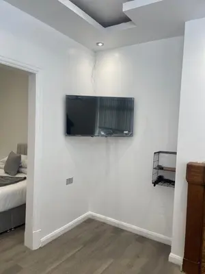 a tv on a white wall in a bedroom at Araan House Hotel -Families and Couples Only in Blackpool