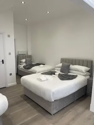 two beds in a room with white walls and wood floors at Araan House Hotel -Families and Couples Only in Blackpool
