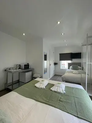 a large white bedroom with two beds and a kitchen at Araan House Hotel -Families and Couples Only in Blackpool