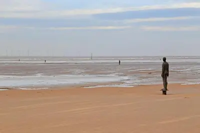 a man standing on the beach looking at the ocean at Lovely 2 Bed Full House By The Beach in Liverpool