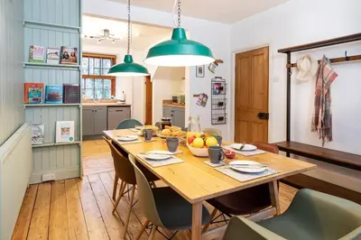 a dining room with a wooden table and green lights at The Riverside Tailor's Retreat at Wray in Wray