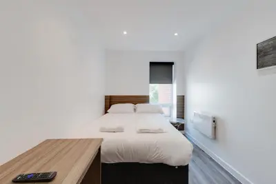 a bedroom with a large bed and a wooden desk at Liverpool Short Stay Apartments in Liverpool