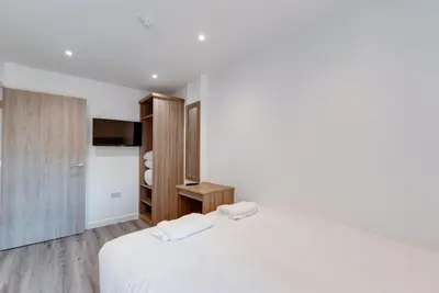 a white bedroom with a bed and a tv at Liverpool Short Stay Apartments in Liverpool