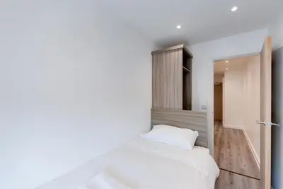 a bedroom with a white bed and a hallway at Liverpool Short Stay Apartments in Liverpool