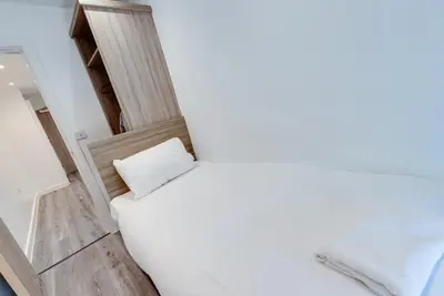 a white room with a bed with a pillow at Liverpool Short Stay Apartments in Liverpool