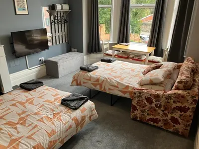 a bedroom with two beds and a couch and a tv at Well-appointed apartment in New Brighton in New Brighton