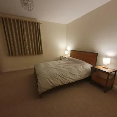 a bedroom with a bed and two tables with lamps at ChurstonBnB, private flat within family home, Bolton in Lostock