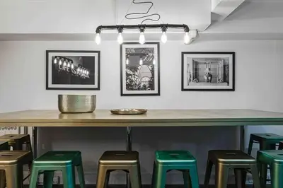 a bar with green stools under a table with pictures at VIP city centre apartment with secure free parking in Liverpool
