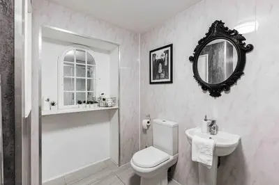 a bathroom with a toilet and a sink and a mirror at VIP city centre apartment with secure free parking in Liverpool